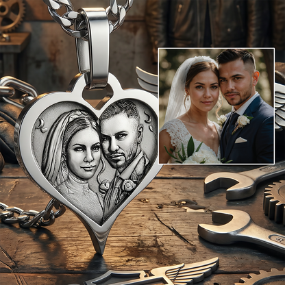 Heart-shaped silver pendant with engraved portrait of a couple on a wooden surface with tools.